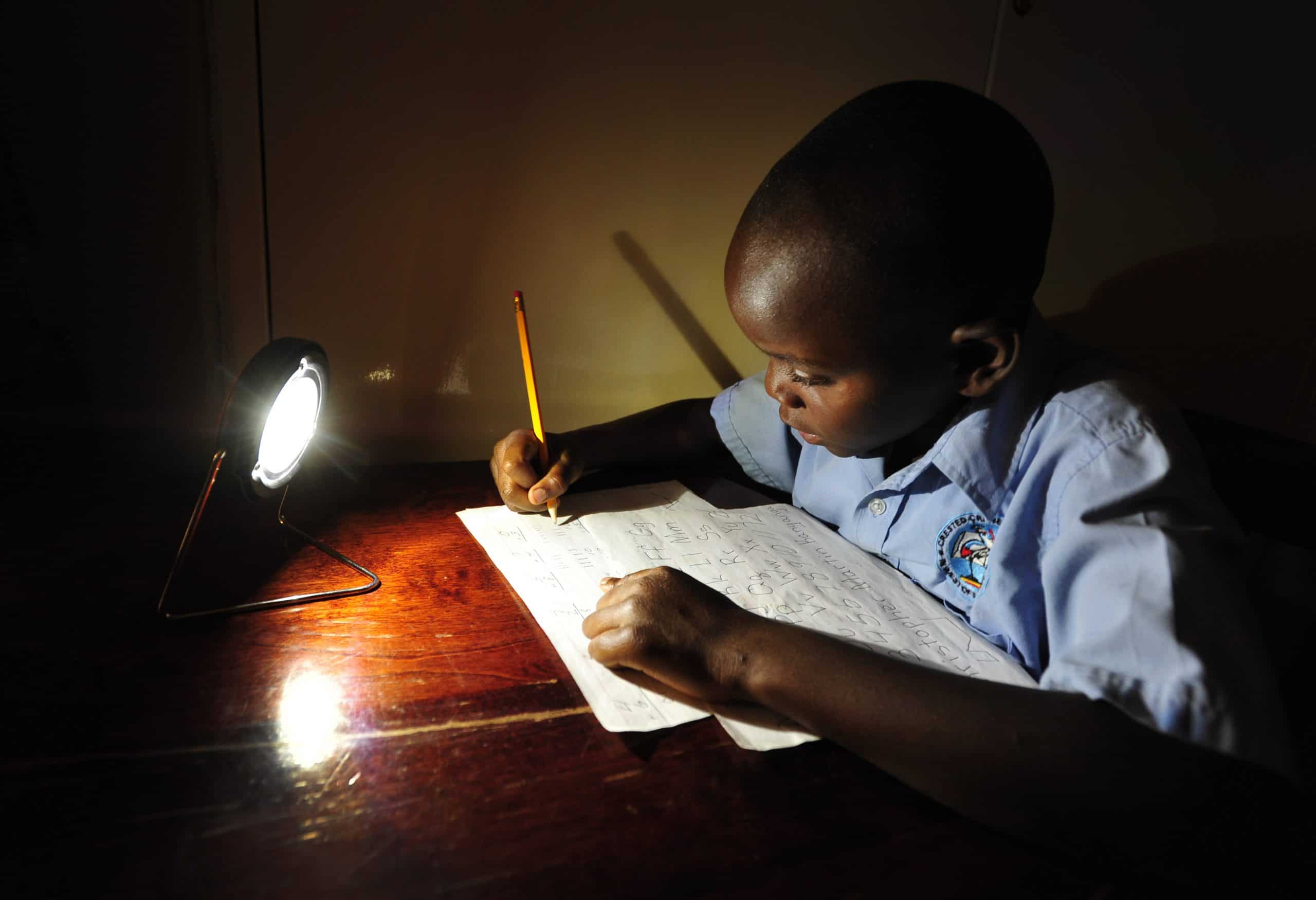 A boy writing by lamplight