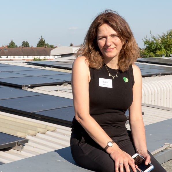 Ashden team member, Cara Jenkinson sitting in front of a row of solar panels