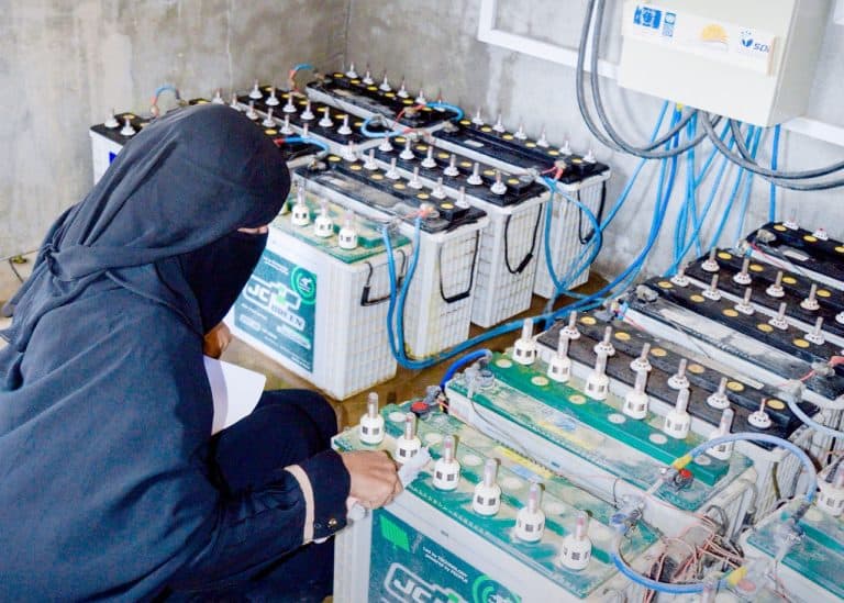 A woman connecting cables to batteries