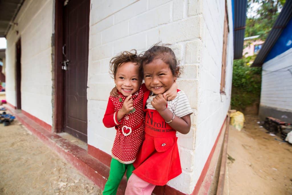 Two children smiling in front of a house
