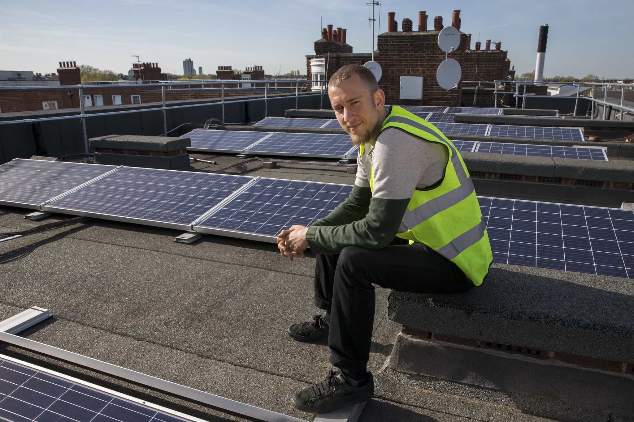 Man on rooftop next to solar panels