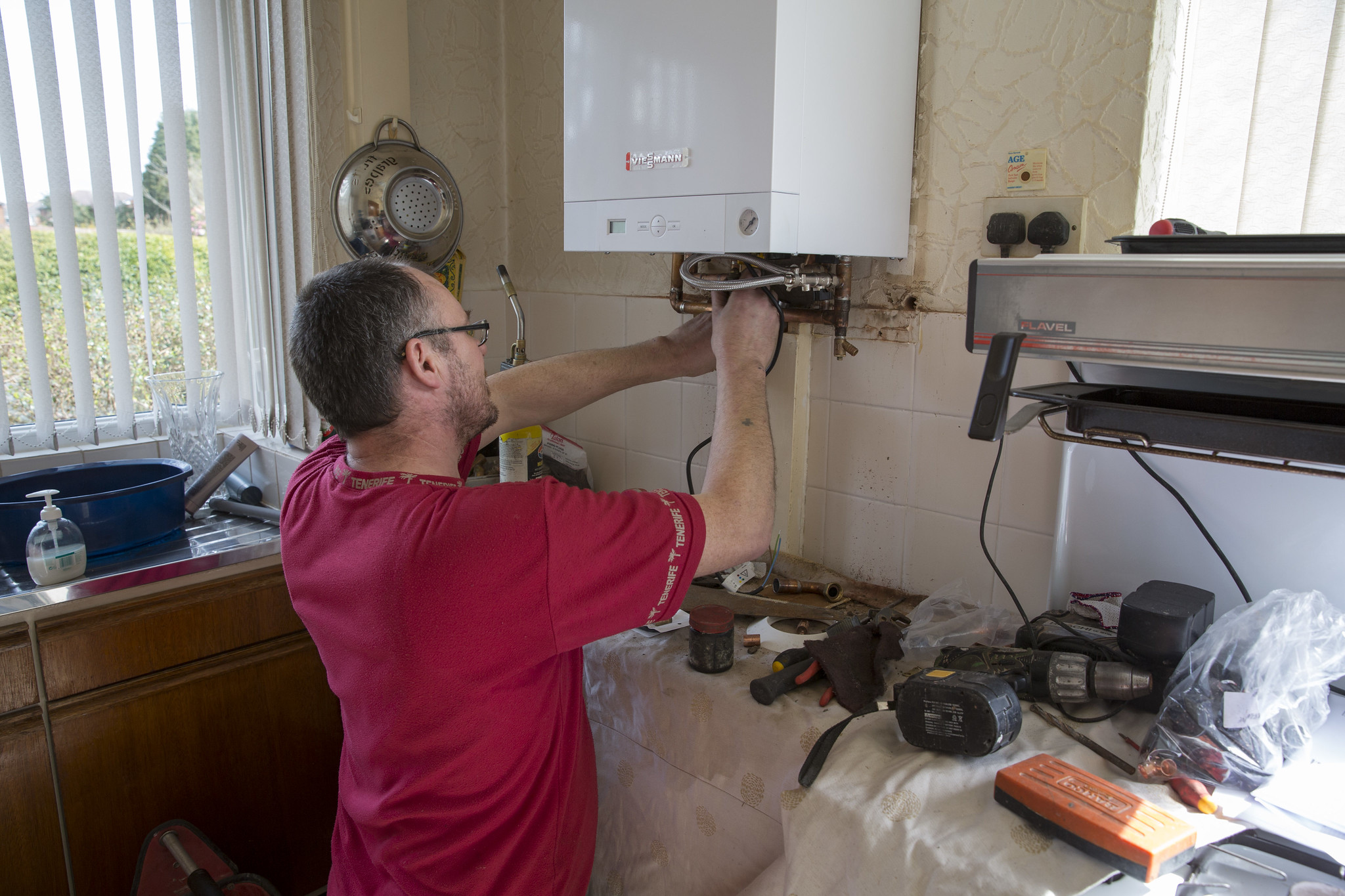 Man working on Viessmann heat pump in a kitchen full of tools.