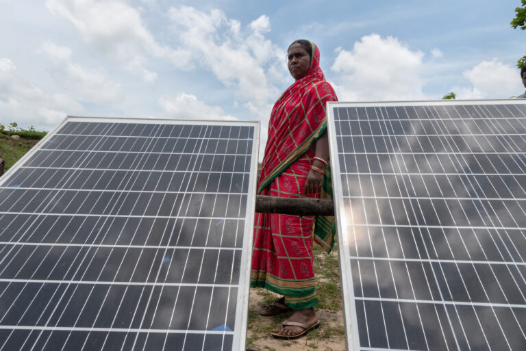 A woman stands behind two solar panels