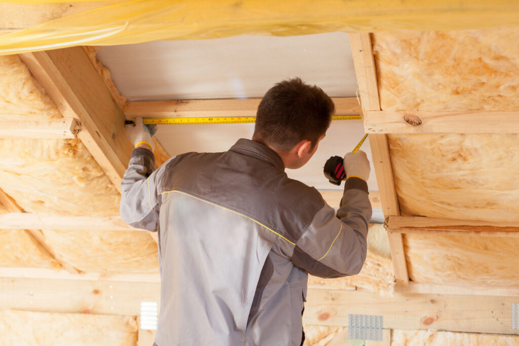 A male roofer with a ruler measuring the loft