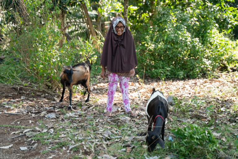 Woman with two goats outside.