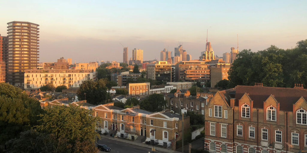 Aerial view of brick terrace houses backed by a view of city skyscrapers at sunset