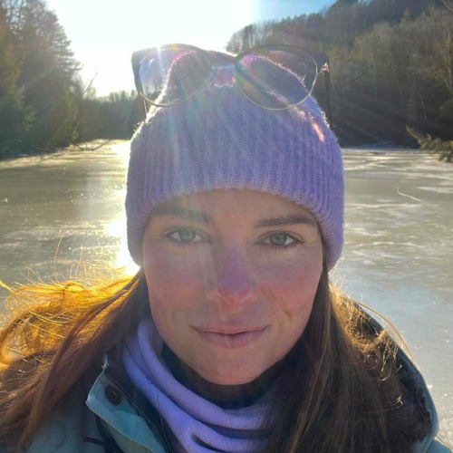 Ashden team member, Dawn Stevenson wearing a purple beanie and smiling with a river in the background