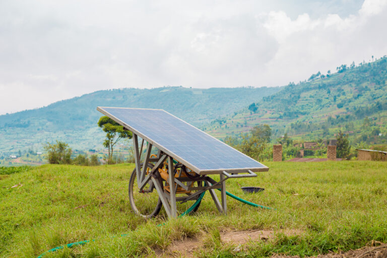 Solar panel mechanism sits in a field backed by mountains.