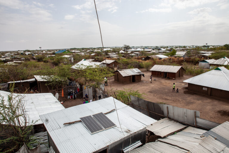 Aerial view of refugee camp with solar panels on roofs.