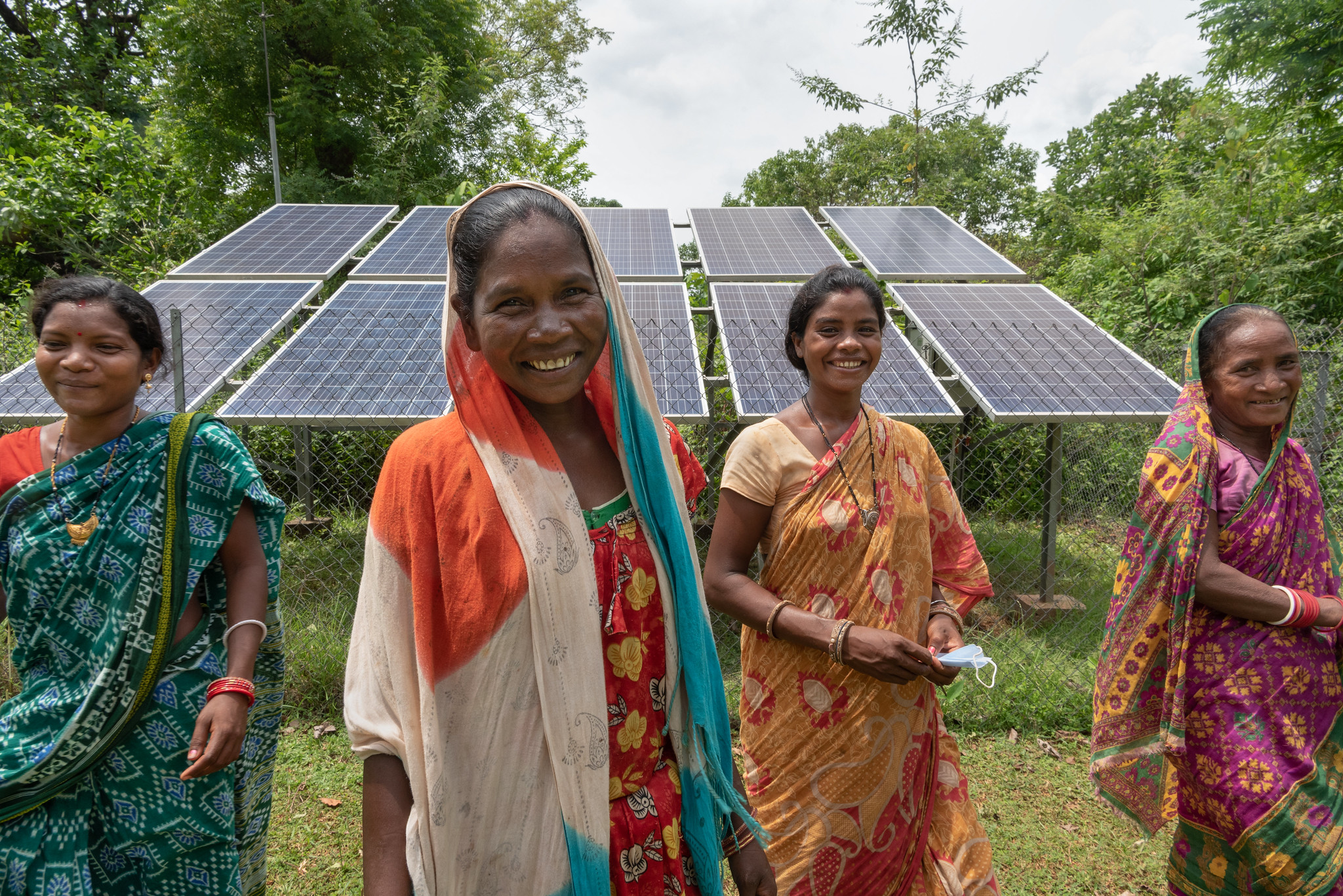 Four women standing in front of a solar panel grid