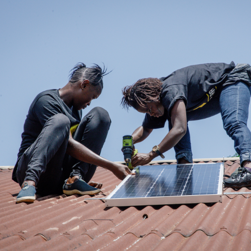 Two people installing a solar panel on a roof