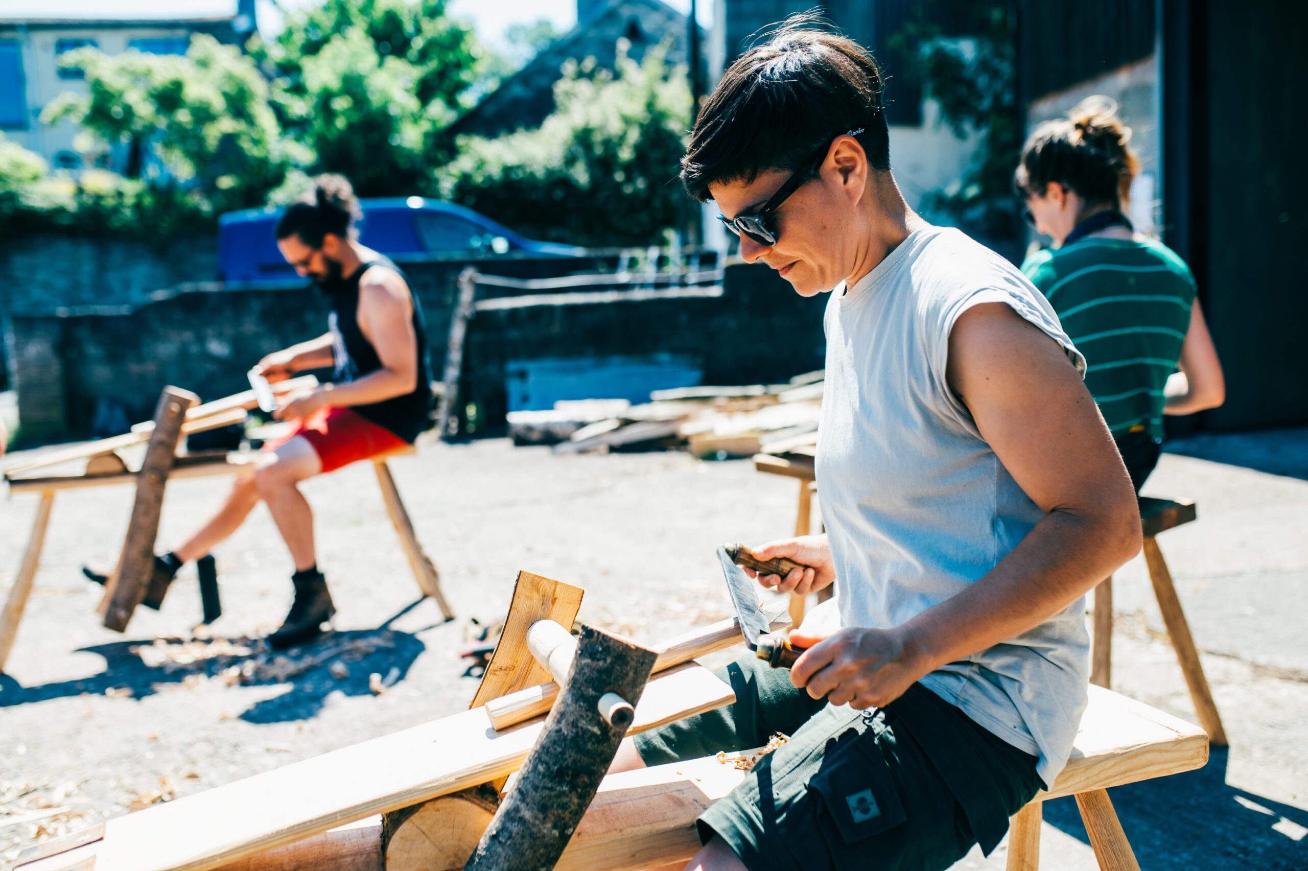 A person sitting and using a saw on wood
