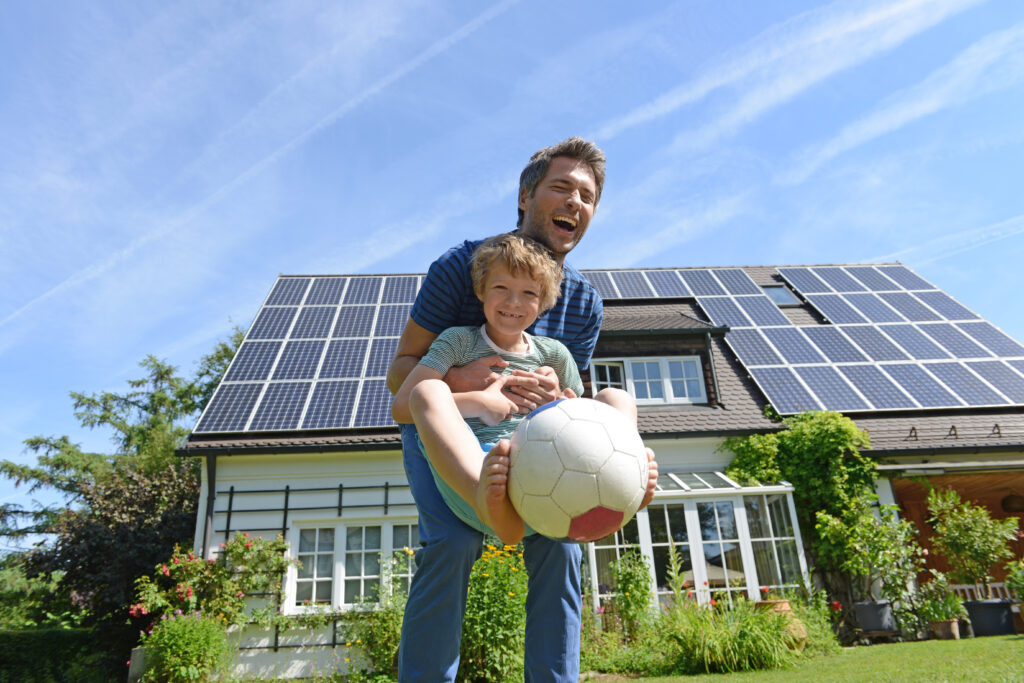 Father and son playing in front of solar panels