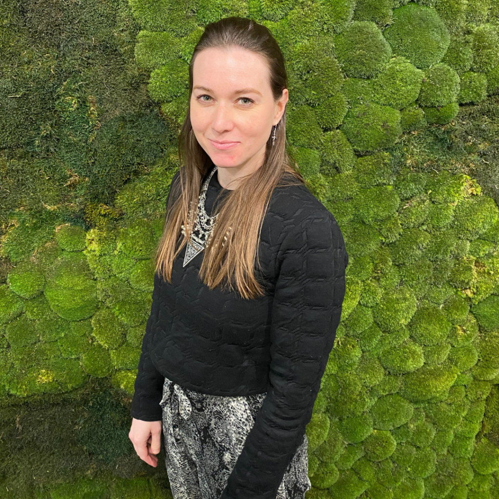 Woman in black top standing in front of a moss wall