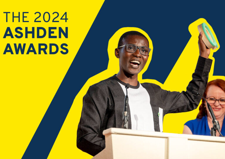 The 2024 Ashden Awards. An award winner is stood on stage whilst raising their award towards the sky in joy.