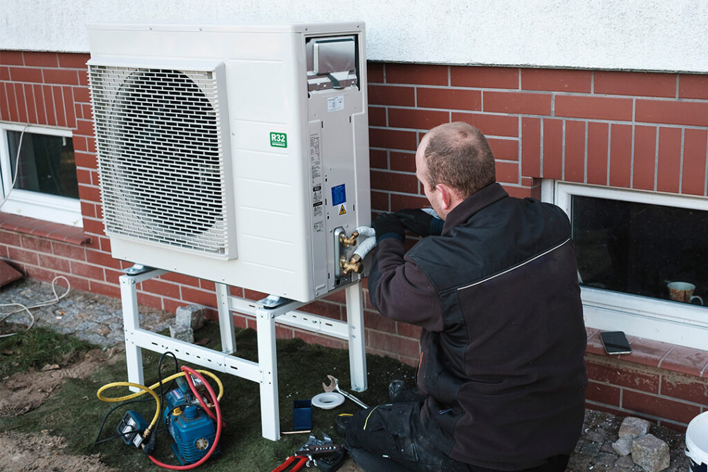 Man installing a heat pump outside