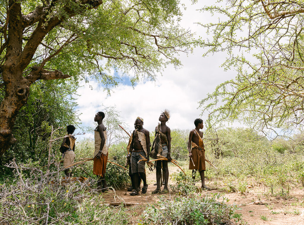 Hazda tribe members climbing a rock in lake Eyasi, Tanzania.